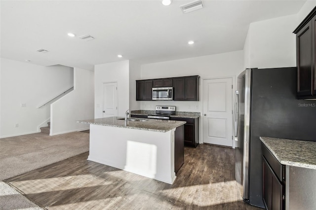 kitchen featuring light stone counters, recessed lighting, visible vents, appliances with stainless steel finishes, and a center island with sink