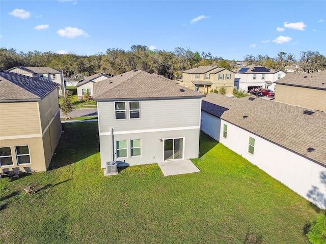 rear view of property with roof with shingles, a lawn, and a residential view