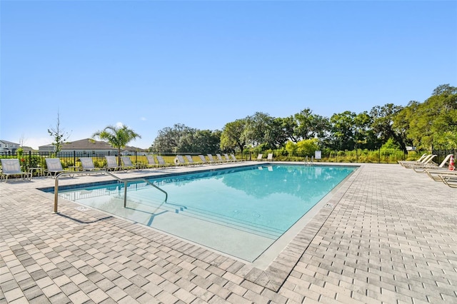 community pool with a patio area and fence