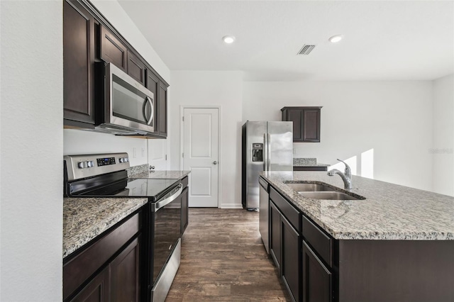 kitchen featuring stainless steel appliances, dark wood-style flooring, a sink, visible vents, and light stone countertops