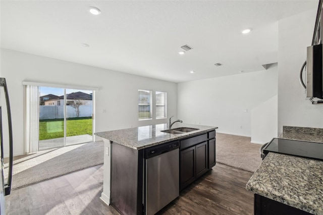 kitchen with visible vents, light stone counters, appliances with stainless steel finishes, open floor plan, and a sink