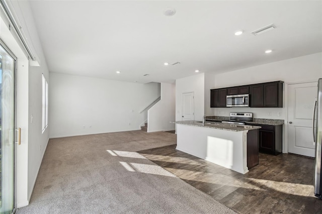 kitchen with a kitchen island with sink, a sink, visible vents, dark brown cabinets, and appliances with stainless steel finishes