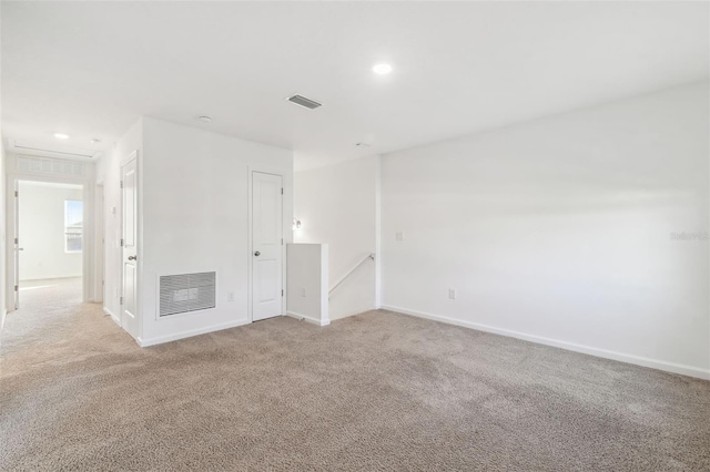 unfurnished room featuring baseboards, visible vents, and light colored carpet