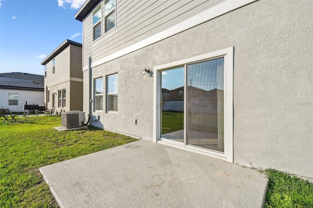 rear view of house featuring a patio area, stucco siding, a yard, and central air condition unit