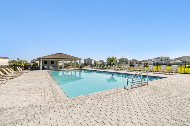 community pool with a patio area, fence, and a residential view