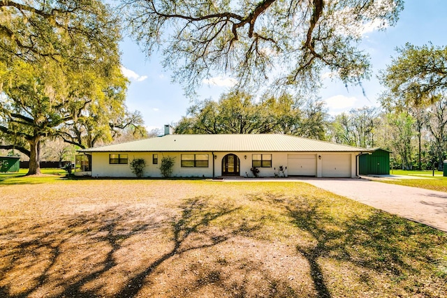 single story home featuring a garage, driveway, metal roof, and a front yard