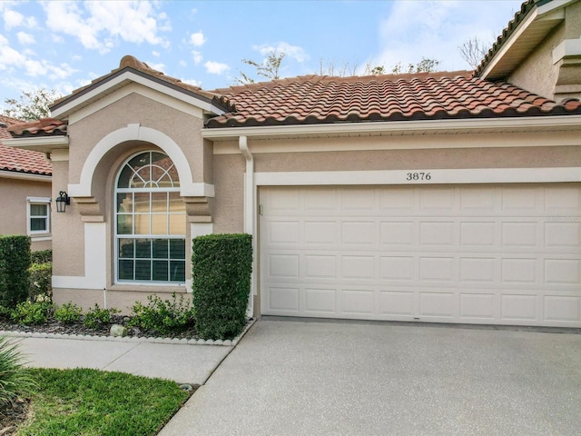 mediterranean / spanish house with driveway, a tile roof, and stucco siding