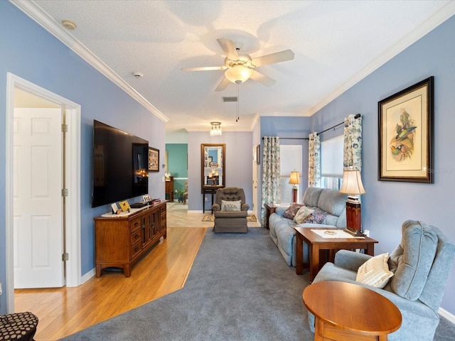 living area featuring a barn door, ornamental molding, light wood-style floors, ceiling fan, and baseboards