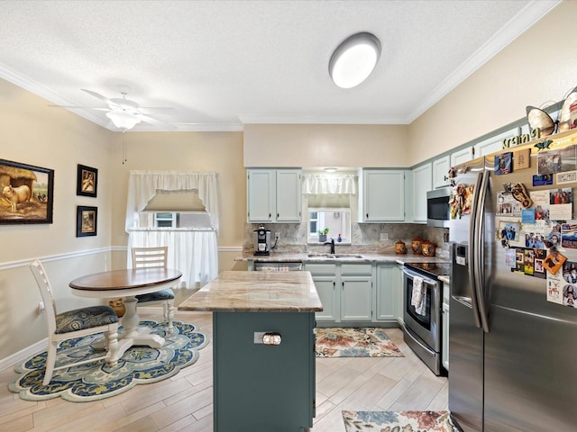 kitchen featuring decorative backsplash, a kitchen island, appliances with stainless steel finishes, a textured ceiling, and a sink