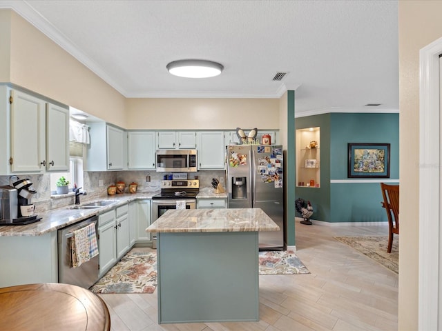 kitchen with visible vents, a kitchen island, a sink, stainless steel appliances, and backsplash