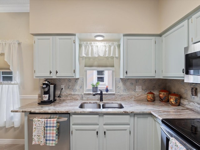 kitchen featuring appliances with stainless steel finishes, backsplash, a sink, and white cabinetry