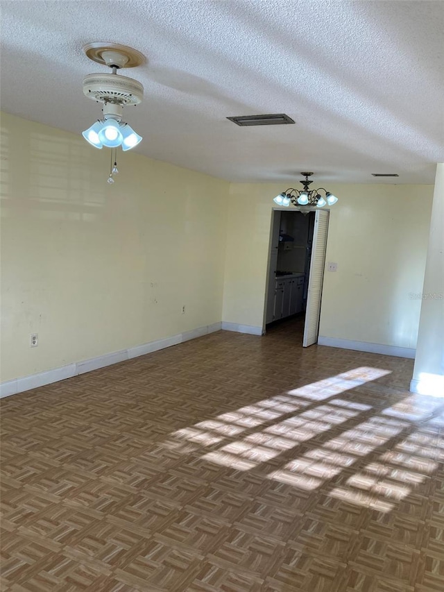 empty room with visible vents, a textured ceiling, and baseboards