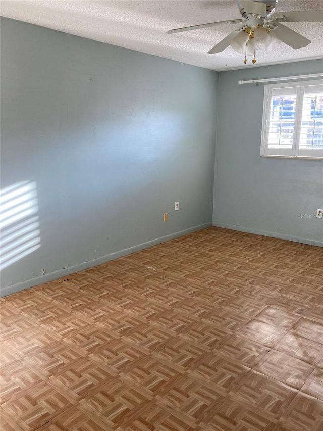 empty room featuring baseboards, a ceiling fan, and a textured ceiling