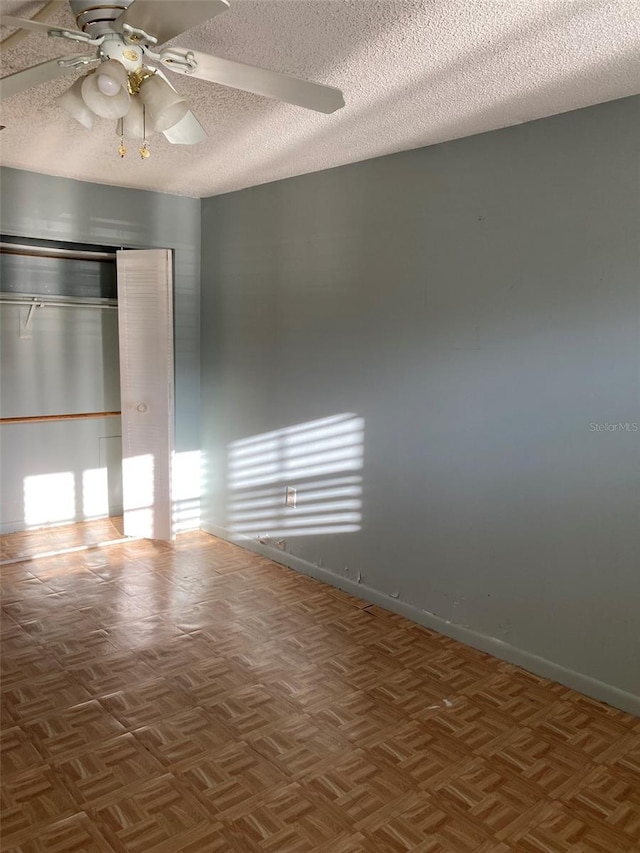 spare room featuring a textured ceiling, baseboards, and a ceiling fan