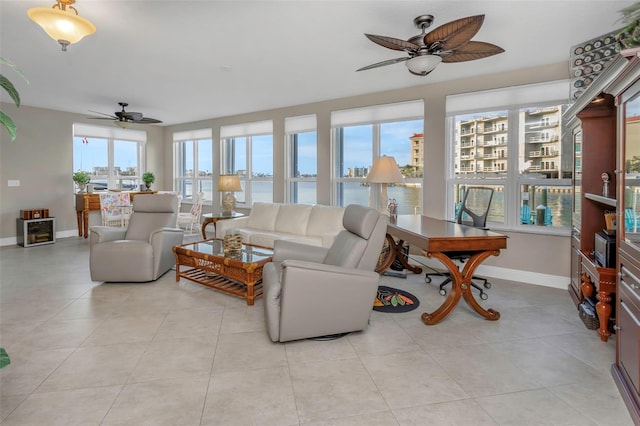 living room with a ceiling fan, baseboards, and light tile patterned floors