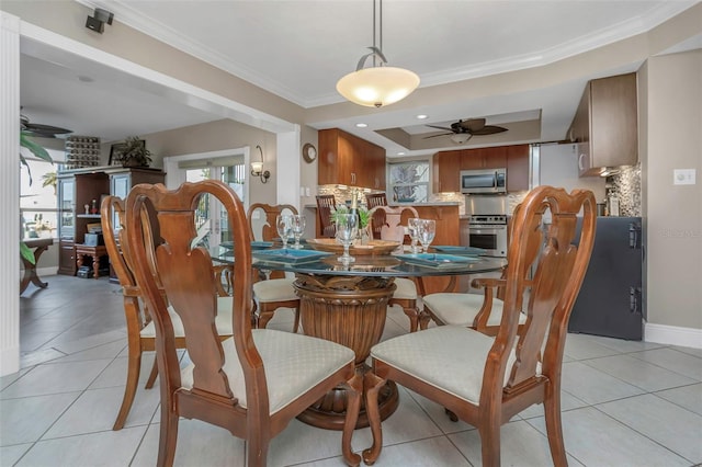 dining area featuring ceiling fan, a tray ceiling, light tile patterned floors, and crown molding