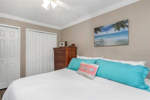 bedroom with a ceiling fan, ornamental molding, and multiple closets