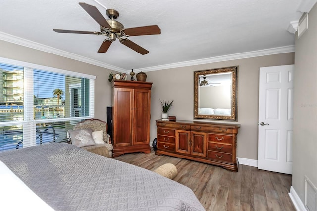 bedroom with baseboards, ornamental molding, ceiling fan, and wood finished floors