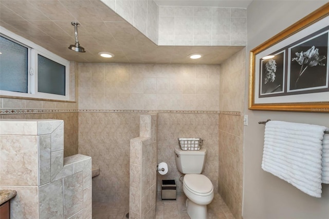 bathroom with toilet, walk in shower, tile patterned flooring, and tile walls