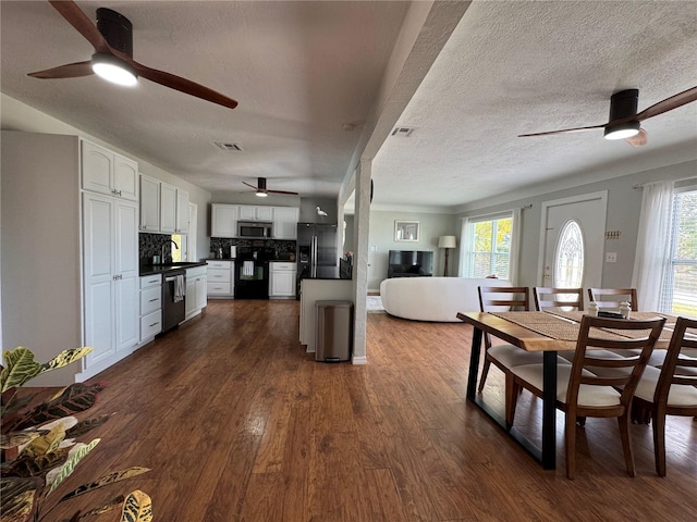 kitchen featuring dark countertops, visible vents, stainless steel microwave, refrigerator with ice dispenser, and dishwashing machine