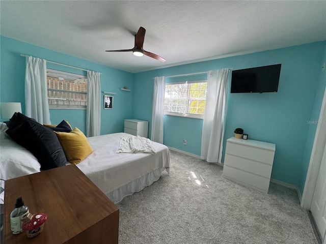 carpeted bedroom with ceiling fan, a textured ceiling, and baseboards