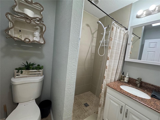 full bathroom with toilet, a stall shower, a textured ceiling, and vanity