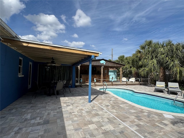 view of swimming pool with a ceiling fan, an outbuilding, an exterior structure, and a patio