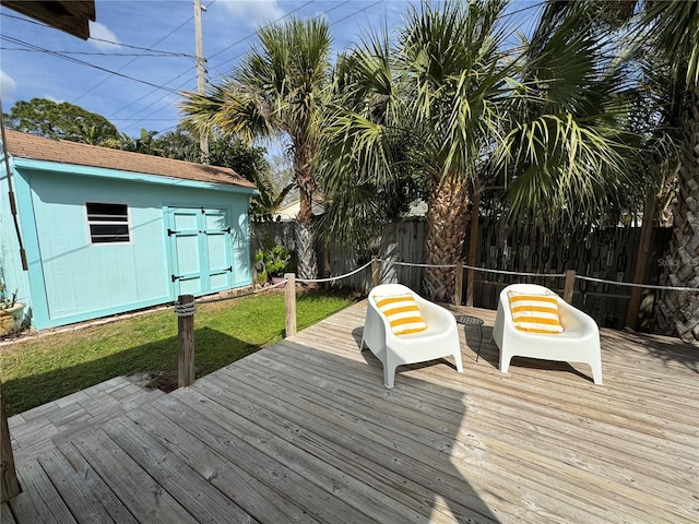 wooden deck with a storage unit, an outdoor structure, and a fenced backyard