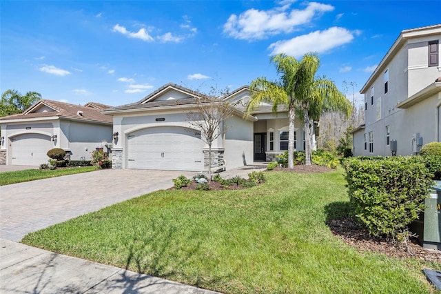 view of front of house with a garage, a tiled roof, decorative driveway, stucco siding, and a front yard