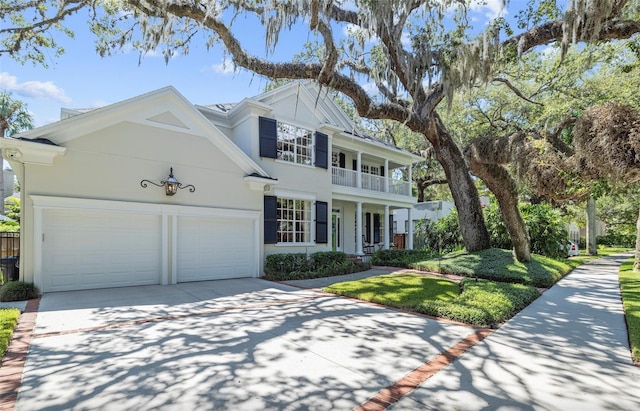 view of front facade with driveway, an attached garage, a balcony, and stucco siding