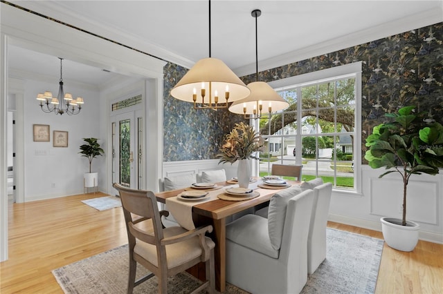 dining space featuring wallpapered walls, ornamental molding, a healthy amount of sunlight, and an inviting chandelier