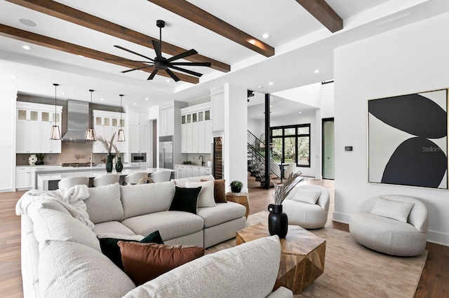 living area featuring ceiling fan, recessed lighting, stairway, light wood-type flooring, and beam ceiling