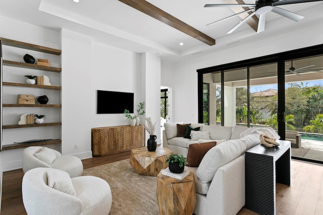 living area with plenty of natural light, a ceiling fan, beam ceiling, and wood finished floors