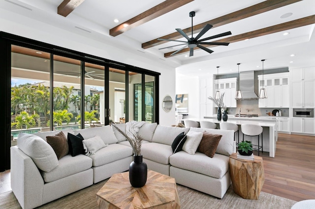 living area featuring ceiling fan, beamed ceiling, light wood-style flooring, and recessed lighting