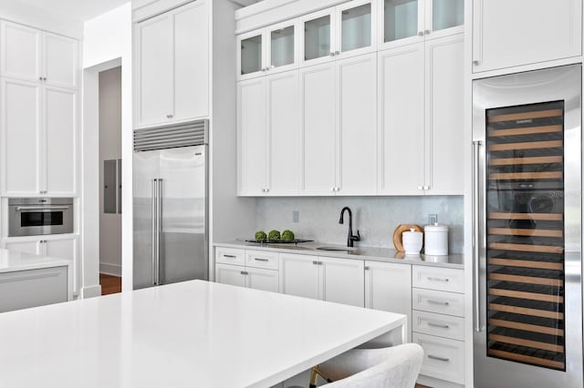 kitchen with beverage cooler, white cabinetry, stainless steel appliances, and light countertops