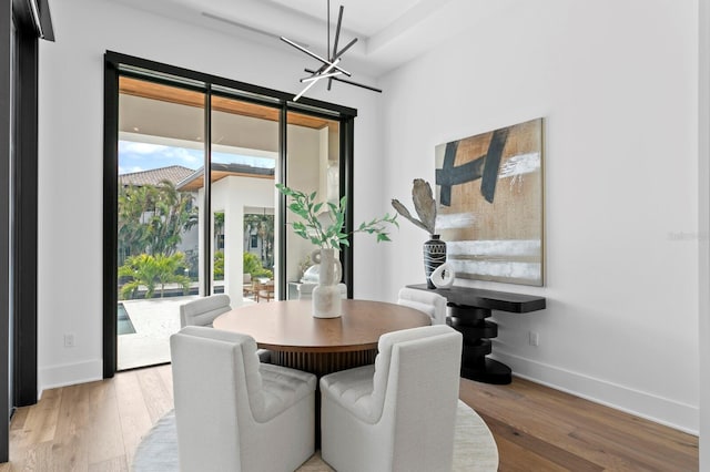 dining area with a notable chandelier, light wood-style flooring, and baseboards