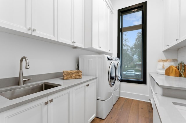 laundry area with cabinet space, wood finished floors, a sink, and washing machine and clothes dryer