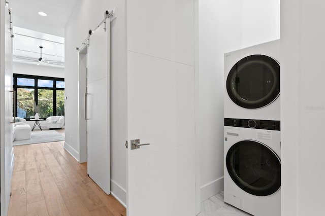 clothes washing area with recessed lighting, a barn door, a ceiling fan, stacked washer / dryer, and laundry area
