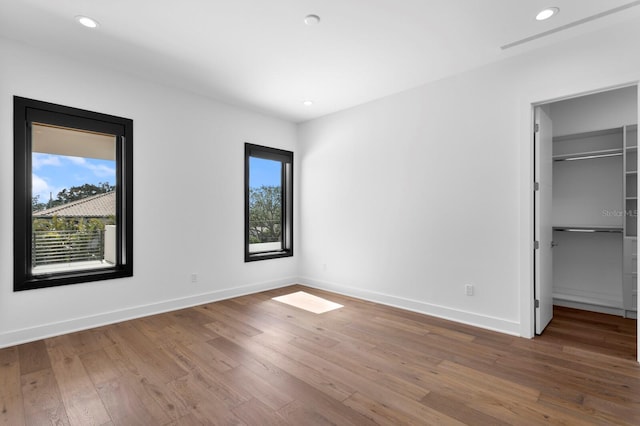 unfurnished bedroom with multiple windows, baseboards, and hardwood / wood-style flooring