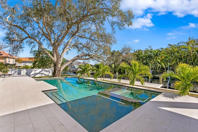 view of swimming pool featuring a pool with connected hot tub, a patio, and fence