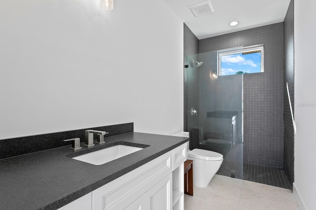 bathroom with toilet, tile patterned floors, tiled shower, and vanity
