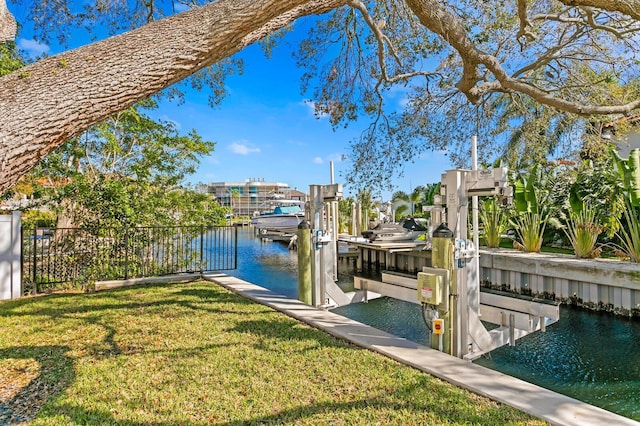 view of dock featuring a lawn, a water view, boat lift, and fence