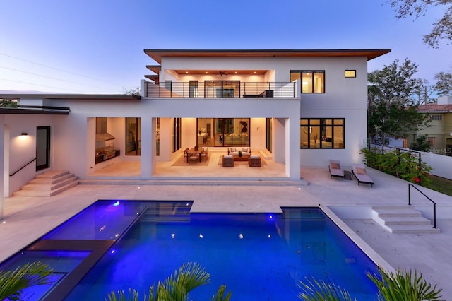 back of property with a patio, a balcony, outdoor lounge area, fence, and stucco siding
