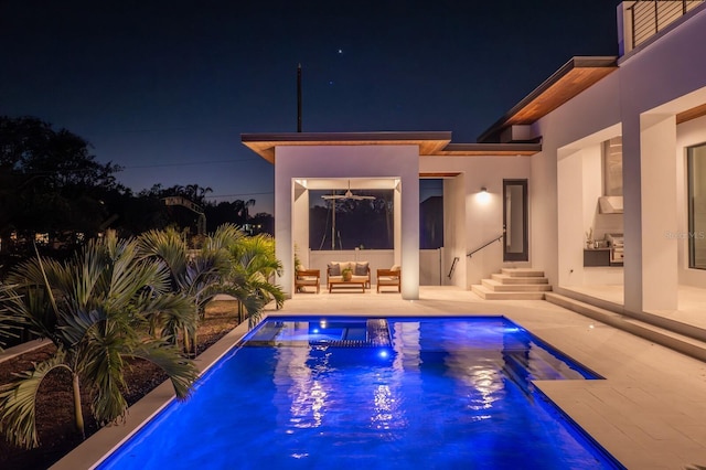 pool at night featuring a patio area, an outdoor living space, and an outdoor pool
