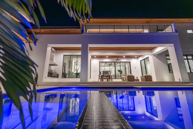 pool at twilight with ceiling fan, outdoor dining area, a patio area, and an outdoor pool