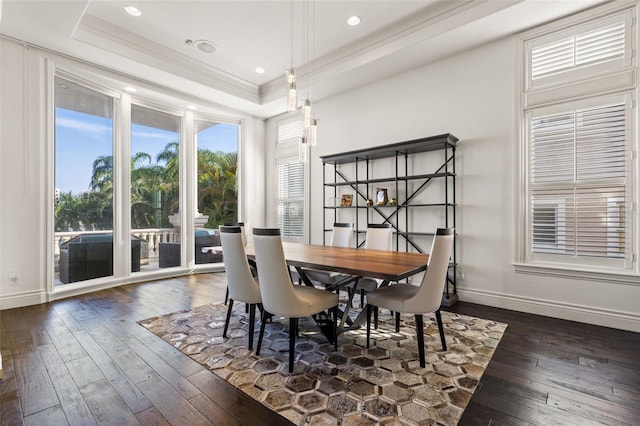 dining area with baseboards, crown molding, a tray ceiling, and dark wood-type flooring