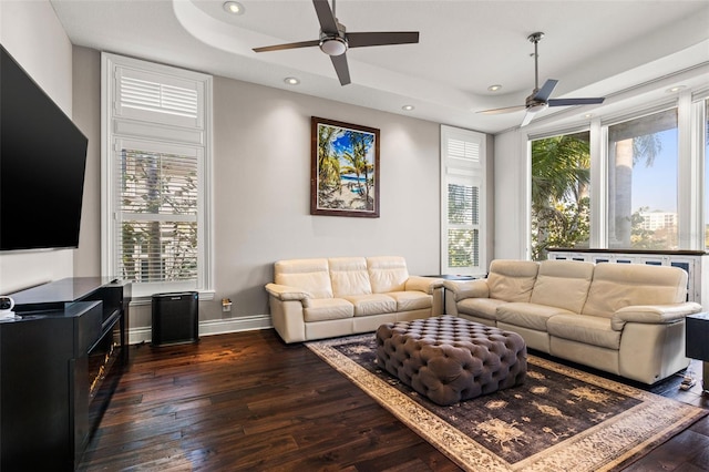 living room with hardwood / wood-style flooring, recessed lighting, a ceiling fan, baseboards, and a tray ceiling