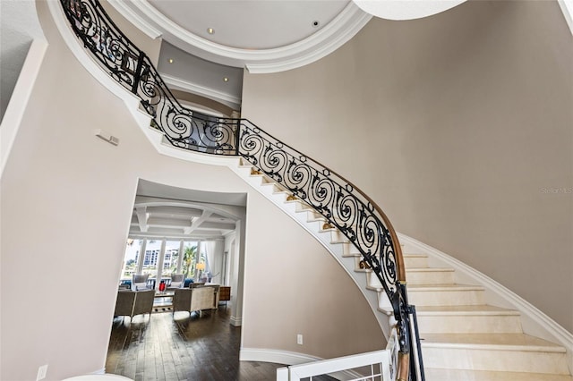 stairs with hardwood / wood-style flooring, coffered ceiling, a towering ceiling, beam ceiling, and crown molding