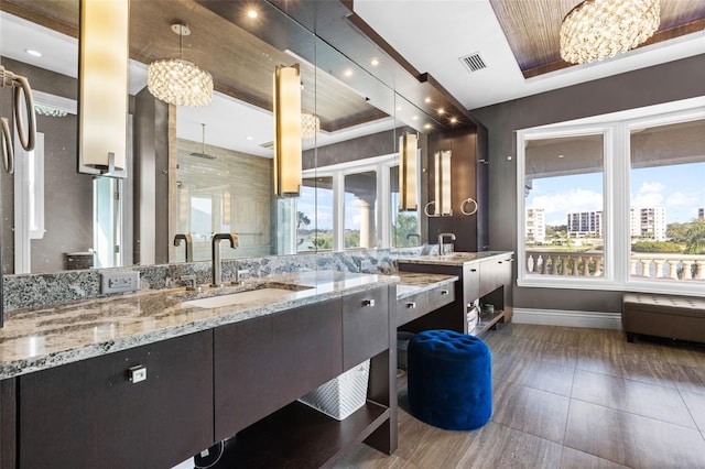 bathroom featuring baseboards, visible vents, a tray ceiling, walk in shower, and vanity