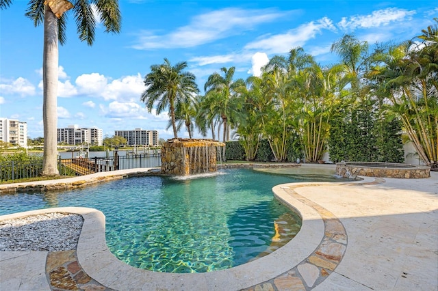 view of pool featuring a view of city, a patio, fence, and a pool with connected hot tub